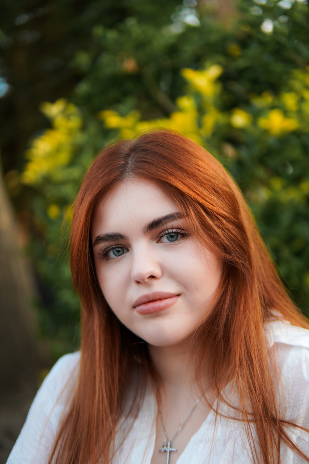 Portrait of a red-haired woman among green foliage