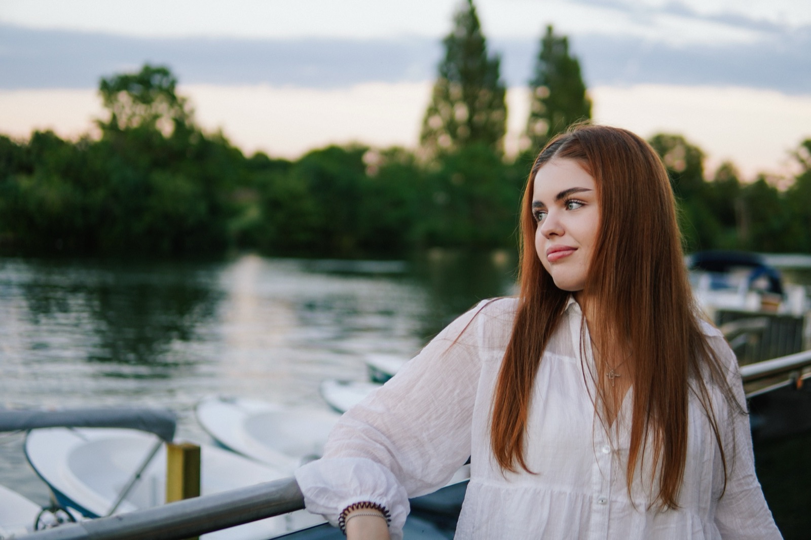 Red-haired woman in a white shirt looking out over the river