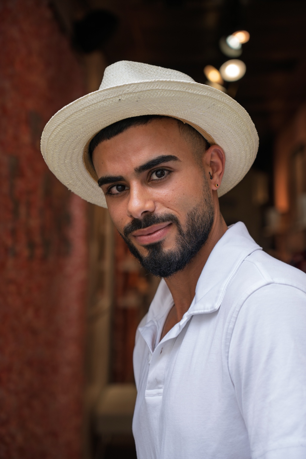Portrait of a bearded man in a straw hat and white polo shirt